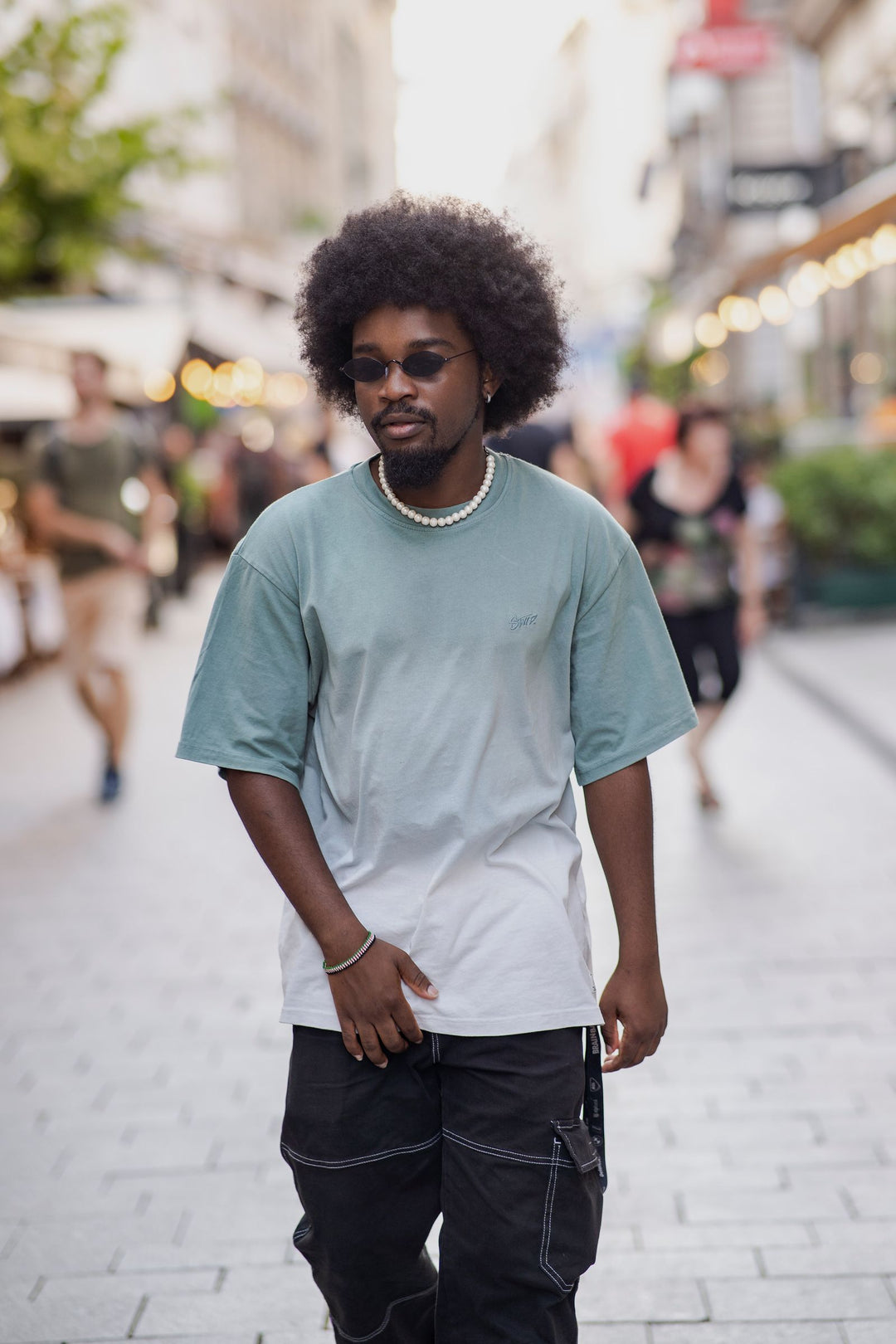 Man styling a pearl necklace with a contemporary streetwear outfit