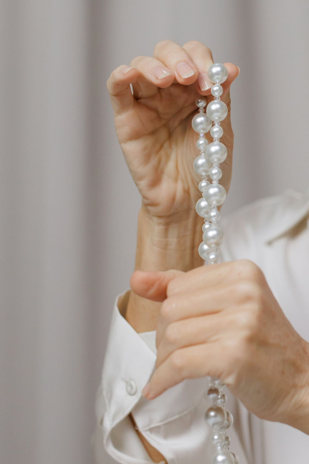 Hands gently holding a pearl necklace for careful handling