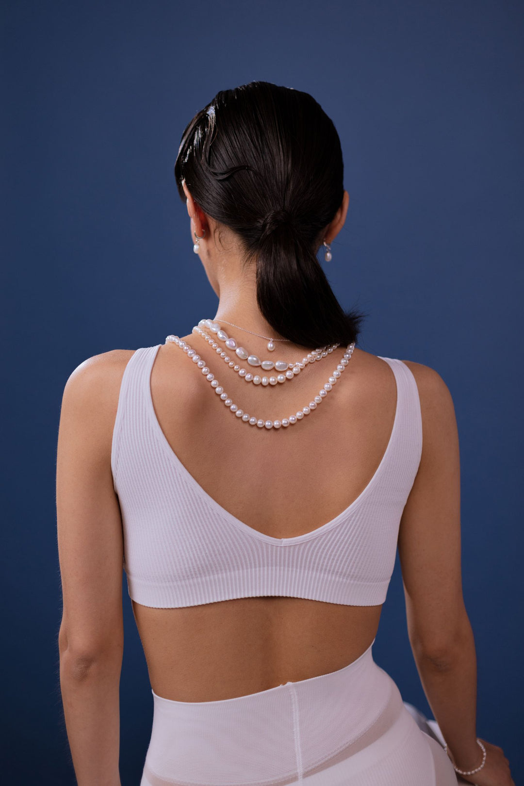 Back view of a woman wearing pearl necklaces at different lengths